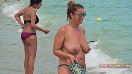 Topless mom playing with her son at the beach